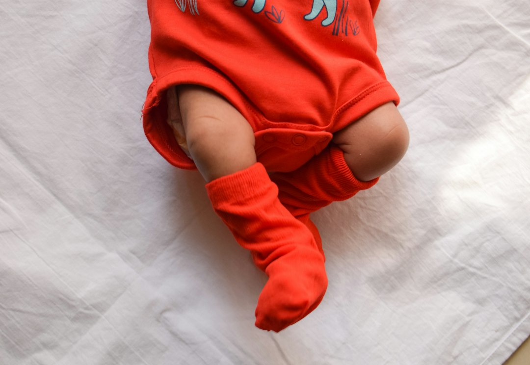 Baby in a red and white onesie resting on white fabric