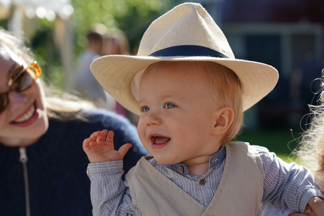Happy baby wearing a sun hat outdoors with a smiling woman